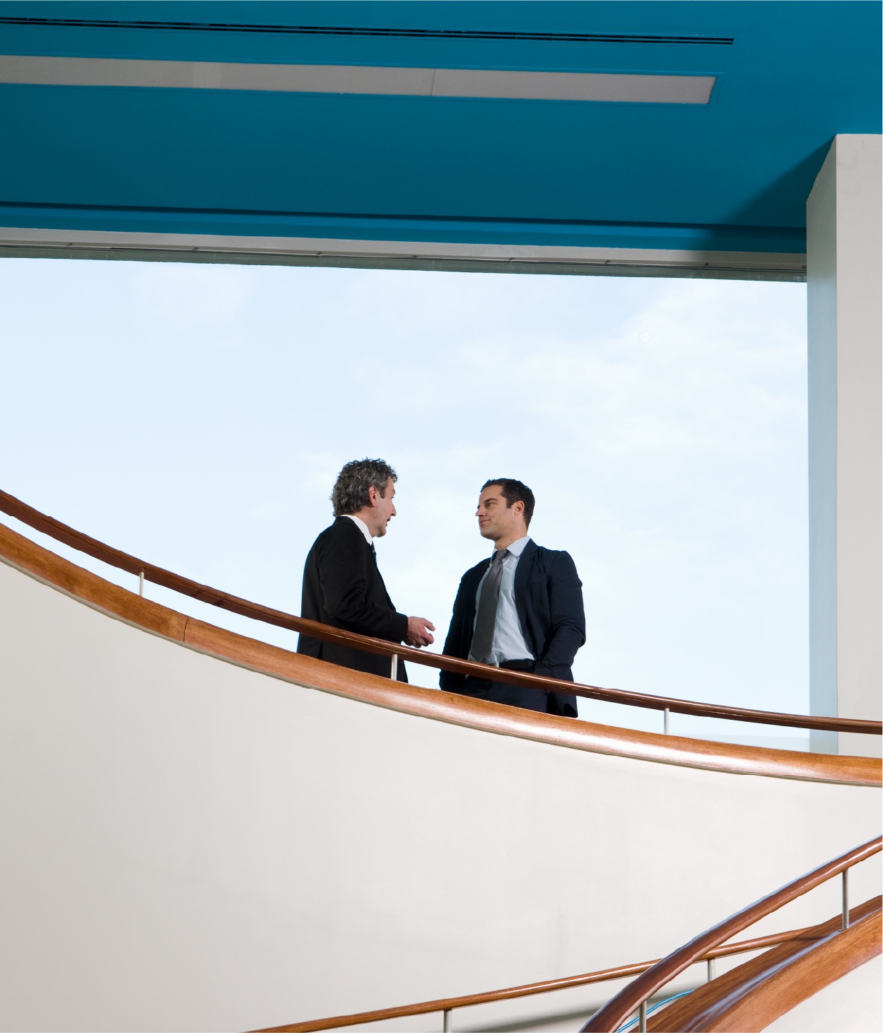 Deux hommes en costume discutant sur un balcon